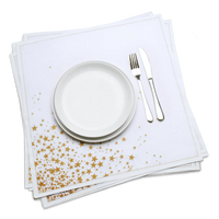 White organic cotton dinner napkin with a gold star print, dressed on a plate with cutlery, by Five Star Napkins.