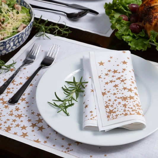 Organic cotton napkin with gold star print folded on white plate, table setting with matching placemat