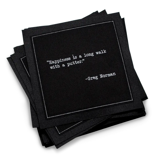 Organic cotton cocktail napkin, black, with white dotted border printed with the Greg Norman quote "Happiness is a long walk with a putter," from Five Star Napkins' Golf Legends quote collection