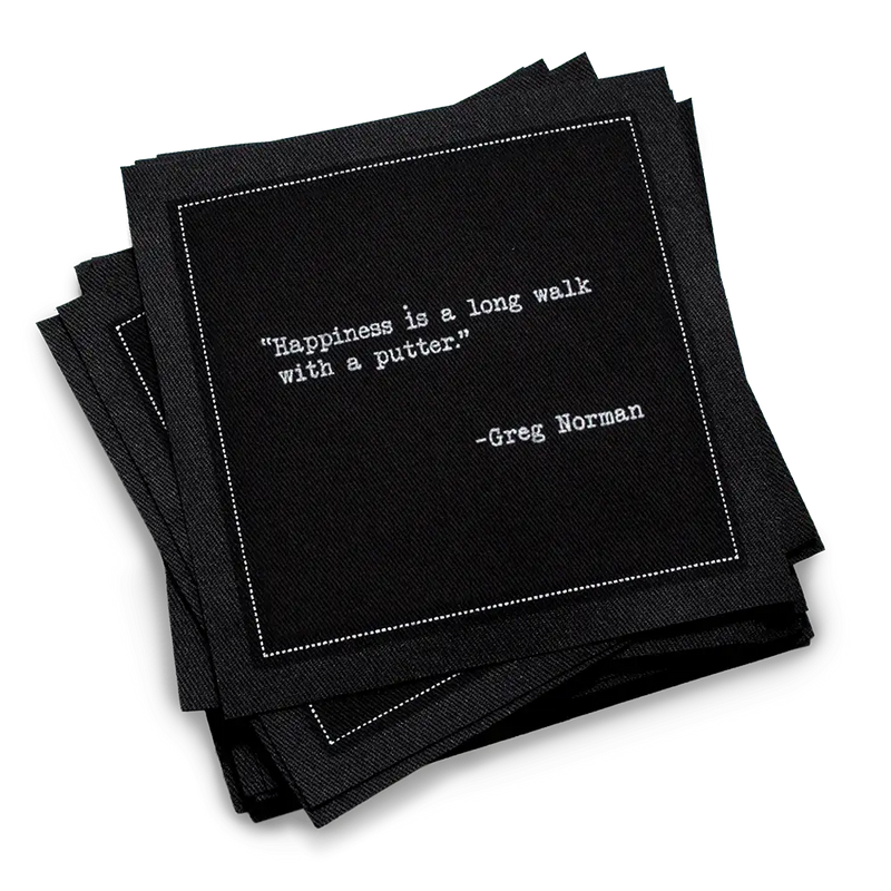 Organic cotton cocktail napkin, black, with white dotted border printed with the Greg Norman quote "Happiness is a long walk with a putter," from Five Star Napkins' Golf Legends quote collection