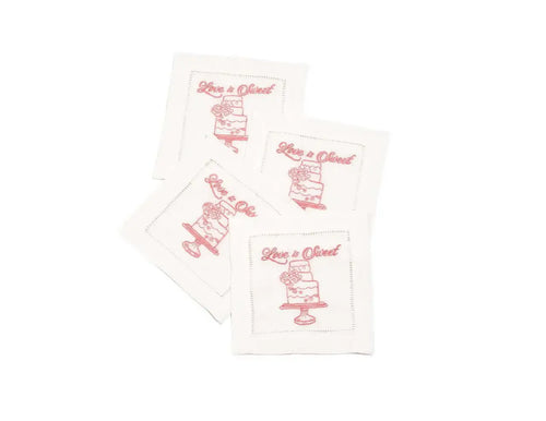 Set of four organic cotton cocktail napkins with 'Love is Sweet' printed quote and cake design.