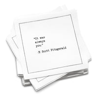 A stack of white Love Quotes cocktail napkins with black dotted borders. The top napkin reads, “It was always you.” —F. Scott Fitzgerald.