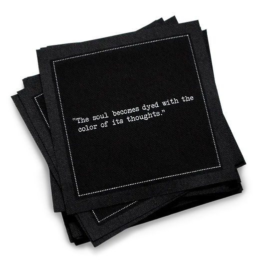 Organic cotton cocktail napkin, black, with white dotted border printed with the quote "The soul becomes dyed with the color of its thoughts," from Five Star Napkins' Marcus Aurelius quote collection