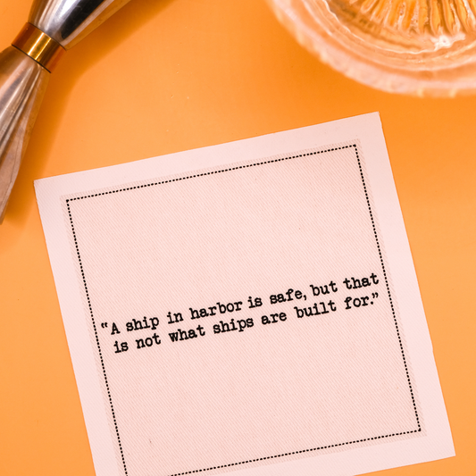 Organic cotton cocktail napkin with quote 'A ship in harbor is safe, but that is not what ships are built for.' on a cocktail party table setting