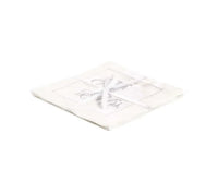 Stack of organic cotton cocktail napkins embroidered with “Mr. & Mrs.” in silver script, tied with a white ribbon, by Five Star Napkins.