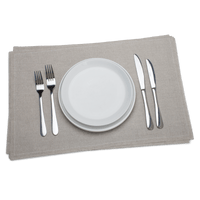 Set of white plates, silver forks, knives, and spoons on a gray placemat with a green background.