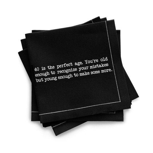 Organic cotton quarter-fold napkin, black, with white dotted border printed with the quote "40 is the perfect age. You're old enough to recognize your mistakes but young enough to make some more," from Five Star Napkins' 40th birthday quote collection
