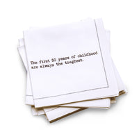 Organic cotton quarter-fold napkin with black dotted border printed with the quote "The first 50 years of childhood are always the toughest," from Five Star Napkins' 50th birthday quote collection