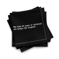 Organic cotton quarter-fold napkin, black, with white dotted border printed with the quote "The first 50 years of childhood are always the toughest," from Five Star Napkins' 50th birthday quote collection