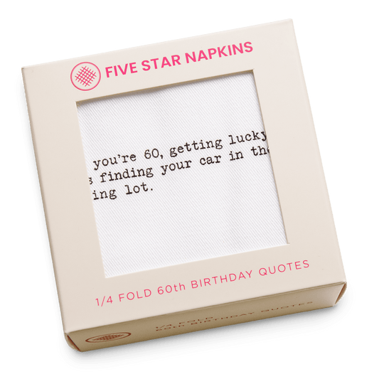 Kraft gift box from Five Star Napkins' 1/4 Fold 60th Birthday Quotes collection, showing an organic cotton quarter-fold napkin printed with the quote "When you're 60, getting lucky means finding your car in the parking lot"