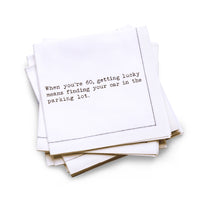 Organic cotton quarter-fold napkin with black dotted border printed with the quote "When you're 60, getting lucky means finding your car in the parking lot," from Five Star Napkins' 60th birthday quote collection