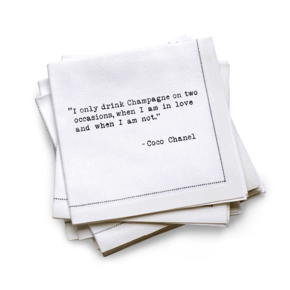 Hero Five Star Napkins' Champagne quote collection, showing a quarter-fold organic cotton cocktail napkin printed with the Coco Chanel quote "I only drink Champagne on two occasions, when I am in love and when I am not"