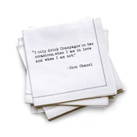 Hero Five Star Napkins' Champagne quote collection, showing a quarter-fold organic cotton cocktail napkin printed with the Coco Chanel quote "I only drink Champagne on two occasions, when I am in love and when I am not"