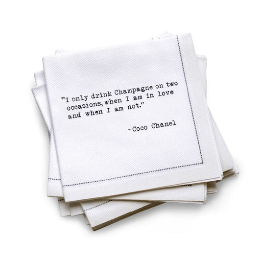 Hero Five Star Napkins' Champagne quote collection, showing a quarter-fold organic cotton cocktail napkin printed with the Coco Chanel quote "I only drink Champagne on two occasions, when I am in love and when I am not"