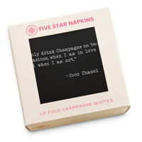 Gift box from Five Star Napkins' Champagne quote collection, showing a quarter-fold organic cotton cocktail napkin, black, printed with the Coco Chanel quote "I only drink Champagne on two occasions, when I am in love and when I am not"