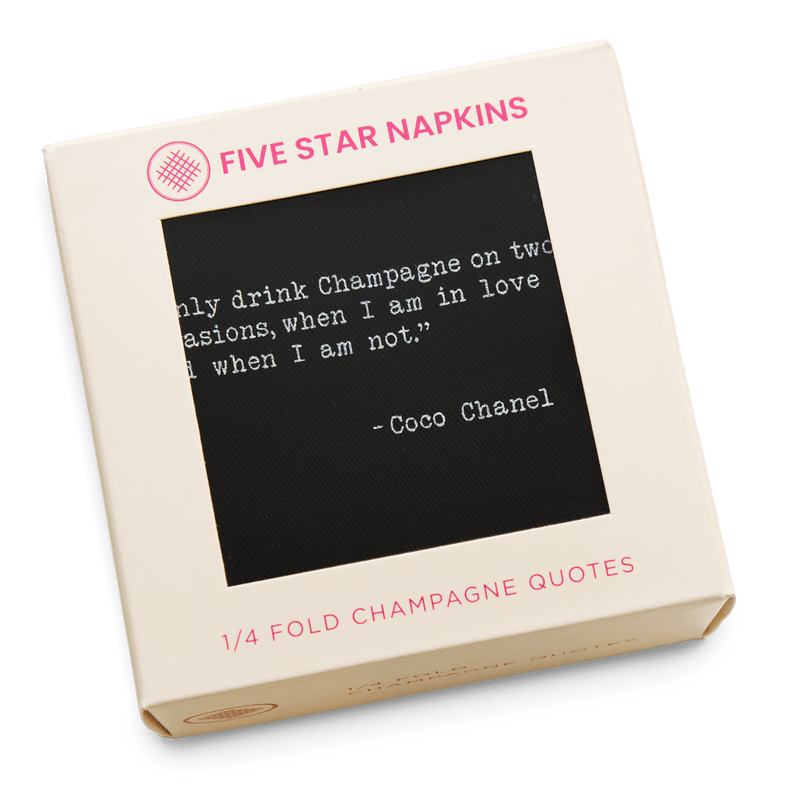 Gift box from Five Star Napkins' Champagne quote collection, showing a quarter-fold organic cotton cocktail napkin, black, printed with the Coco Chanel quote "I only drink Champagne on two occasions, when I am in love and when I am not"