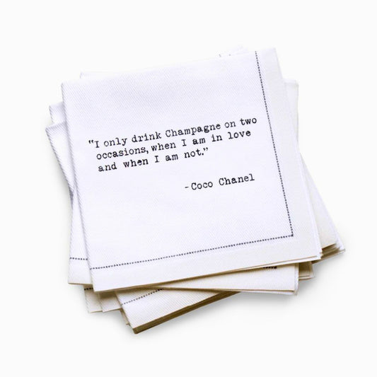 Quarter-fold organic cotton cocktail napkin with black dotted border printed with the Coco Chanel quote "I only drink Champagne on two occasions, when I am in love and when I am not," from Five Star Napkins' Champagne quote collection