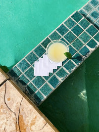 White organic cotton cocktail napkins with a margarita glass by a poolside on turquoise tiles