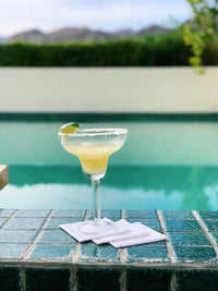 Margarita glass with lime on white organic cotton cocktail napkins by a poolside