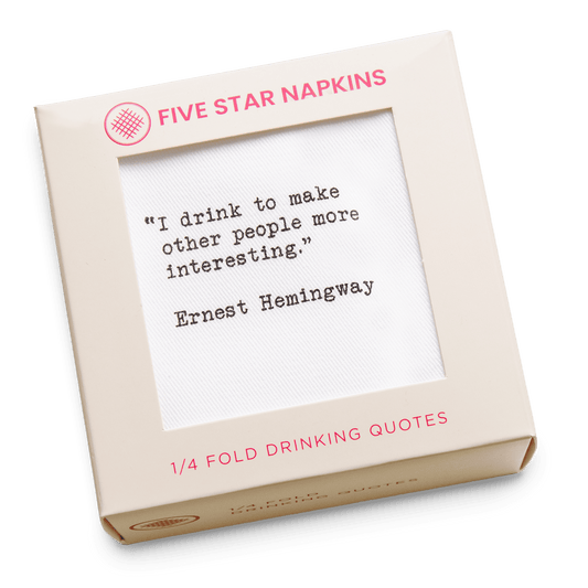 Kraft gift box from Five Star Napkins' Drinking Quotes First Edition collection, showing a quarter-fold organic cotton cocktail napkin printed with the quote "I drink to make other people more interesting"