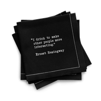 Quarter-fold organic cotton cocktail napkin, black, with white dotted border printed with the quote "I drink to make other people more interesting," from Five Star Napkins' Drinking Quotes First Edition collection