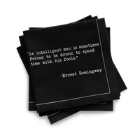 Organic cotton quarter-fold napkin, black, with white dotted border printed with the quote "An intelligent man is sometimes forced to be drunk to spend time with his fools," from Five Star Napkins' Drinking Quotes Second Edition collection