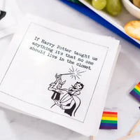 Organic cotton cocktail napkin with 'If Harry Potter taught us anything it's that no one should live in the closet' quote, styled on a table with rainbow flags and snacks.