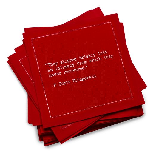 A stack of red Love Quotes cocktail napkins with white dotted borders. The top napkin reads, “They slipped briskly into an intimacy from which they never recovered.” —F. Scott Fitzgerald.