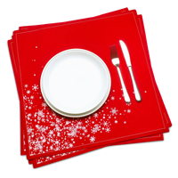Red organic cotton dinner napkin with white snowflake cascade pattern, set beneath a plate and silverware, by Five Star Napkins.