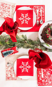 Holiday table setting with red organic cotton napkins featuring white snowflake design, matching placemats and festive decor.