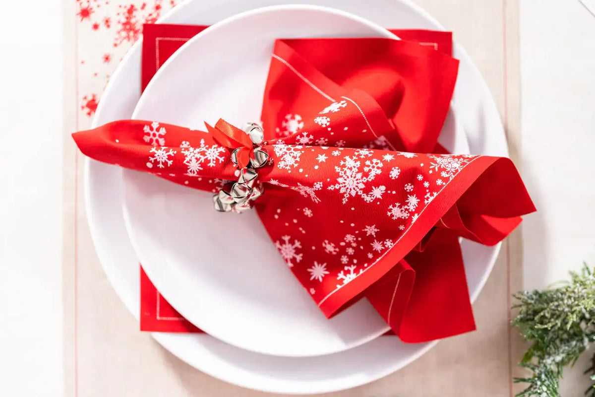 Toreador organic cotton napkin with white snowflake print, folded on a holiday place setting