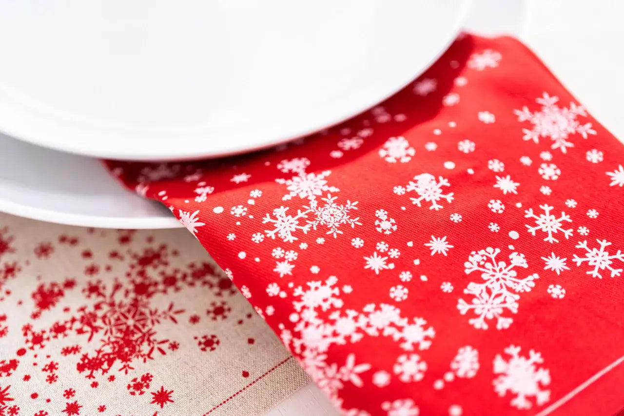 Red organic cotton napkin with white snowflake pattern under plate, festive table setting