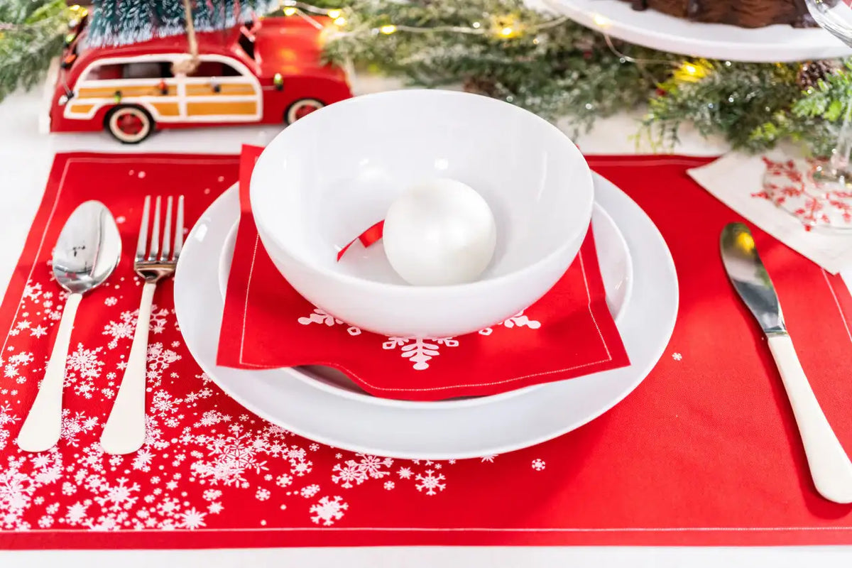 Red organic cotton placemat and napkin with white snowflake pattern on holiday table setting