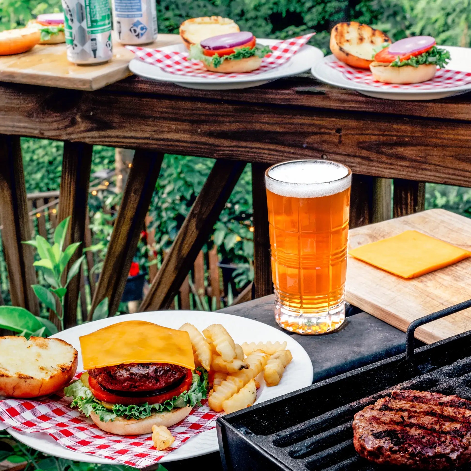 Outdoor table setting with burgers, fries, beer, and red gingham organic cotton napkins