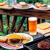 Outdoor table setting with burgers, fries, beer, and red gingham organic cotton napkins