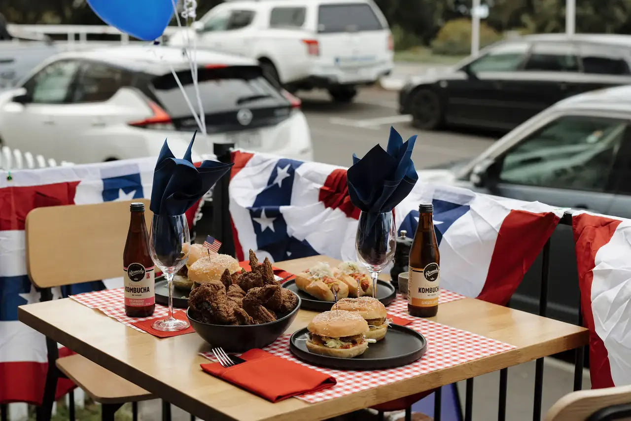Outdoor table setting with blue and Persimmon organic cotton napkins, burgers and fried chicken, festive party decor