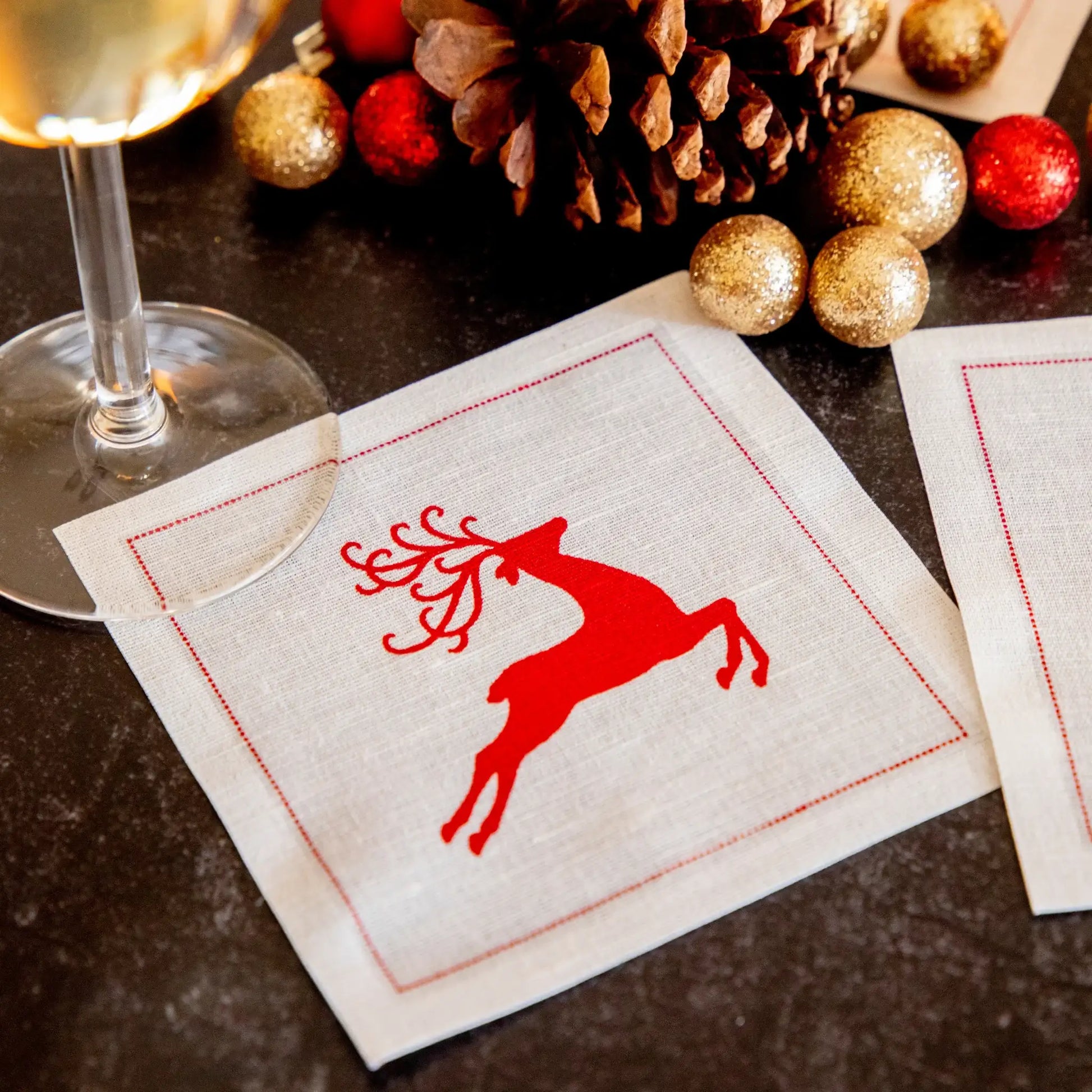 organic cotton cocktail napkin with red reindeer design in holiday table setting