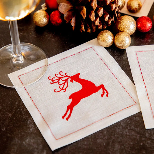 organic cotton cocktail napkin with red reindeer design in holiday table setting