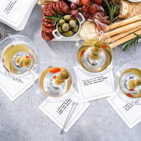 Luxury cocktail napkins under martini glasses with charcuterie and breadsticks on table.