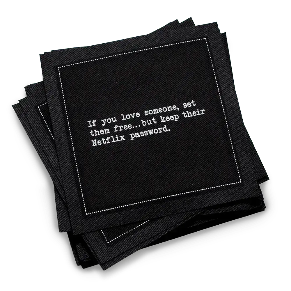 Stack of black organic cotton cocktail napkins printed with the quote “If you love someone, set them free…but keep their Netflix password,” from Five Star Napkins’ Relationship quote collection.