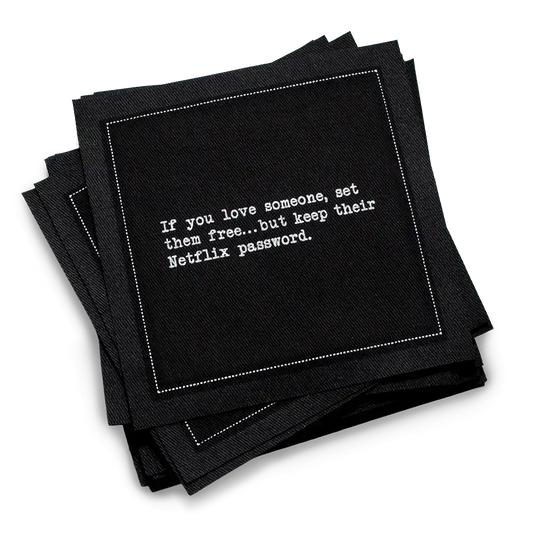 Stack of black organic cotton cocktail napkins printed with the quote “If you love someone, set them free…but keep their Netflix password,” from Five Star Napkins’ Relationship quote collection.