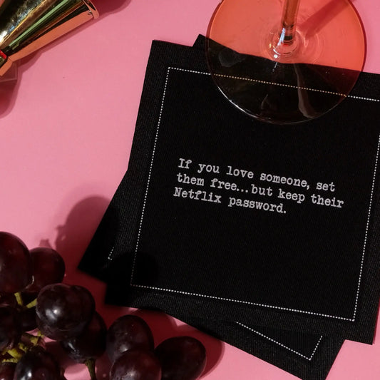 Anthracite Grey organic cotton cocktail napkin with printed quote, wine glass, grapes, and lipstick on a pink surface