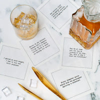 Organic cotton cocktail napkins with humorous quarantine quotes, styled on a marble table with a drink and gold utensils.