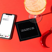 Organic cotton cocktail napkin, black, printed with the quote "I am not arguing, I'm just explaining why I am right," styled on a red background with a margarita, a phone, and a chili pepper, from Five Star Napkins' Snarky quote collection