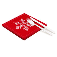 Stack of red organic cotton napkins in Toreador with white snowflake design and white cutlery