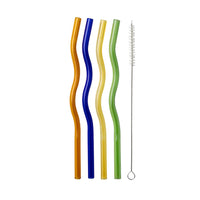 Four wavy glass straws in orange, blue, yellow, and green with a cleaning brush, flat lay on a white background.
