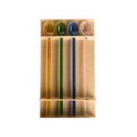 Four glass cocktail swizzle spoons in yellow, green, blue, and pink displayed in their kraft packaging tray.