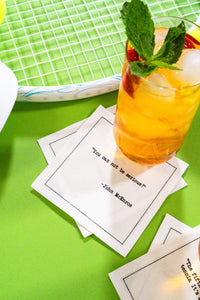 Organic cotton cocktail napkins printed with the quote “You cannot be serious!” – John McEnroe, styled with a mint cocktail on a green court background, from Five Star Napkins’ Tennis Legends quote collection.