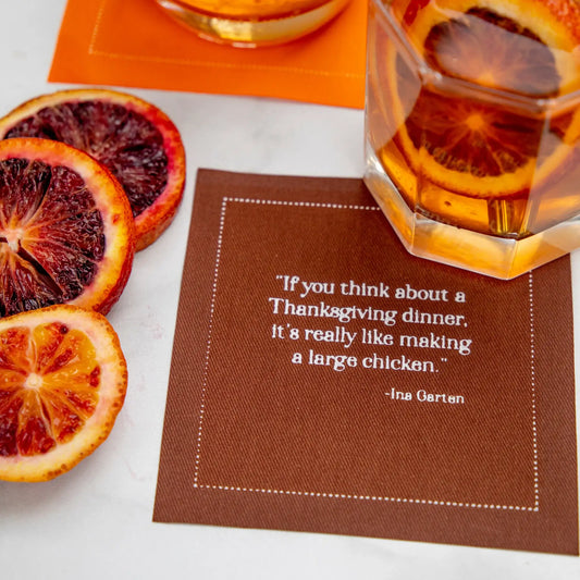 Organic cotton cocktail napkin in Pickled Beet with quote, styled with cocktail and blood orange slices