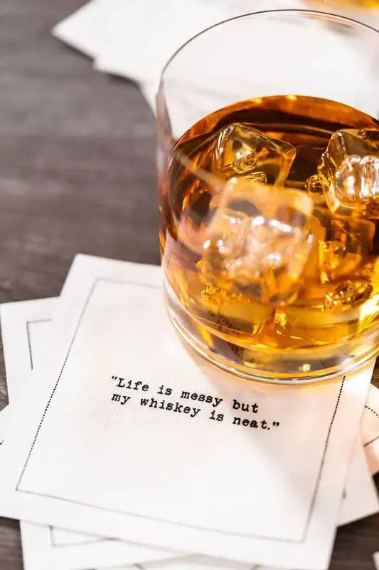Organic cotton cocktail napkin with quote 'Life is messy but my whiskey is neat,' under whiskey glass